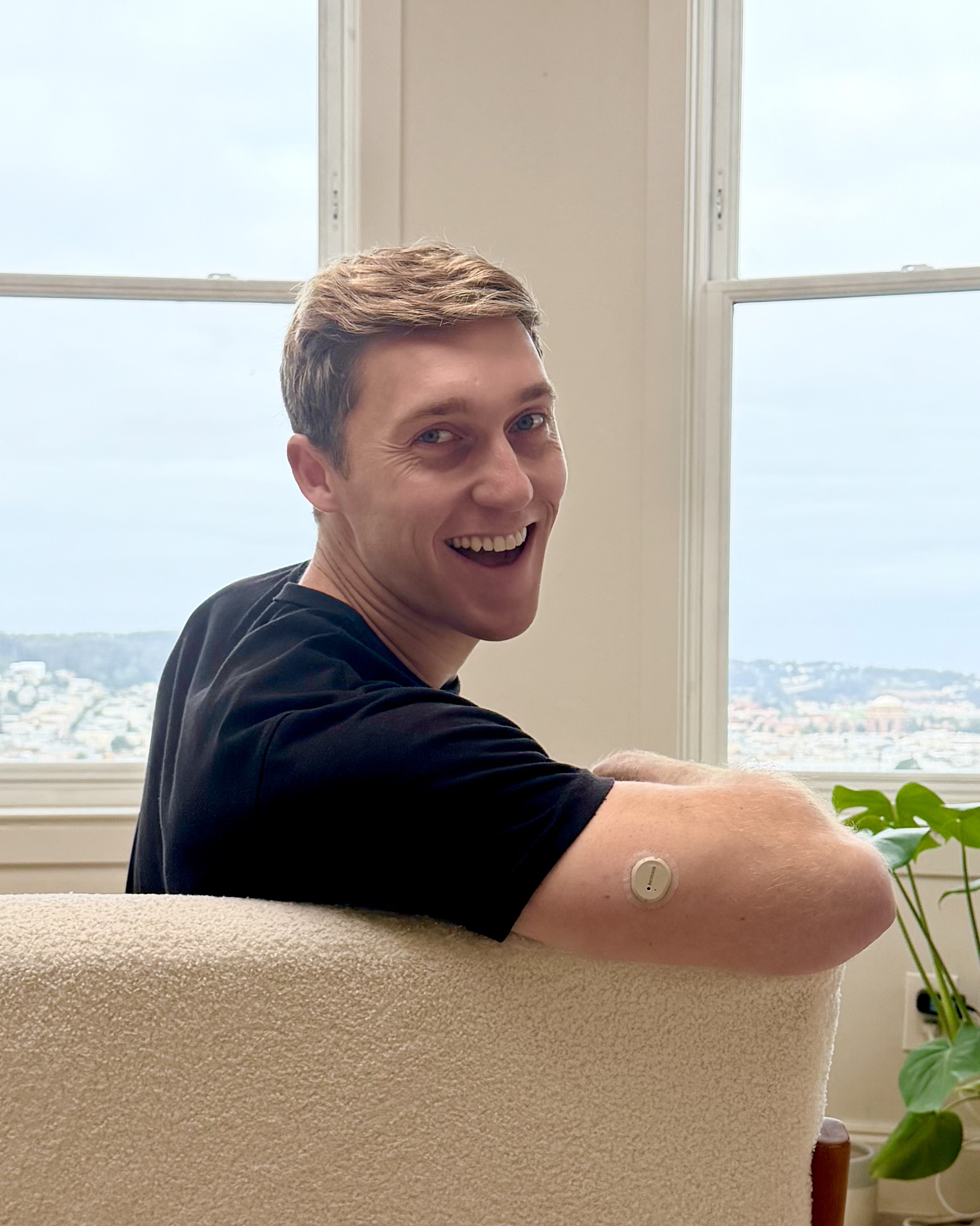 Man smiling while wearing a CGM sensor on his arm